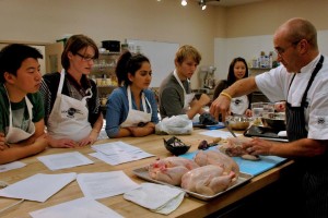 Trainees watching with rapt attention as chef shows them how to prepare a chicken